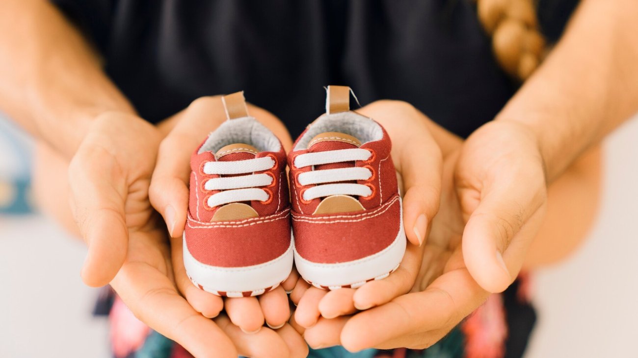 newborn-concept-with-couple-holding-shoes-hands_23-2147665675